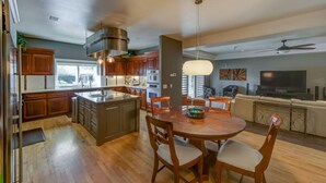 A modern kitchen with wooden cabinets, a central island, and a dining area with a round table and chairs.