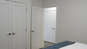Ein Schlafzimmer mit einem Bett, zwei weißen Türen und einem Flur, der in einen anderen Raum führt.