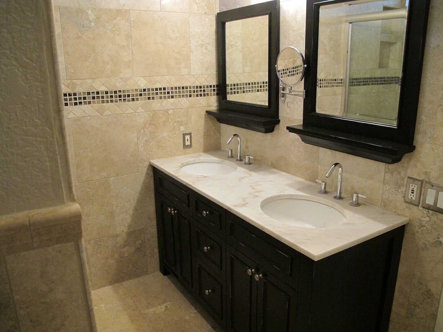 A bathroom with two sinks, dark cabinets, and a tiled backsplash.