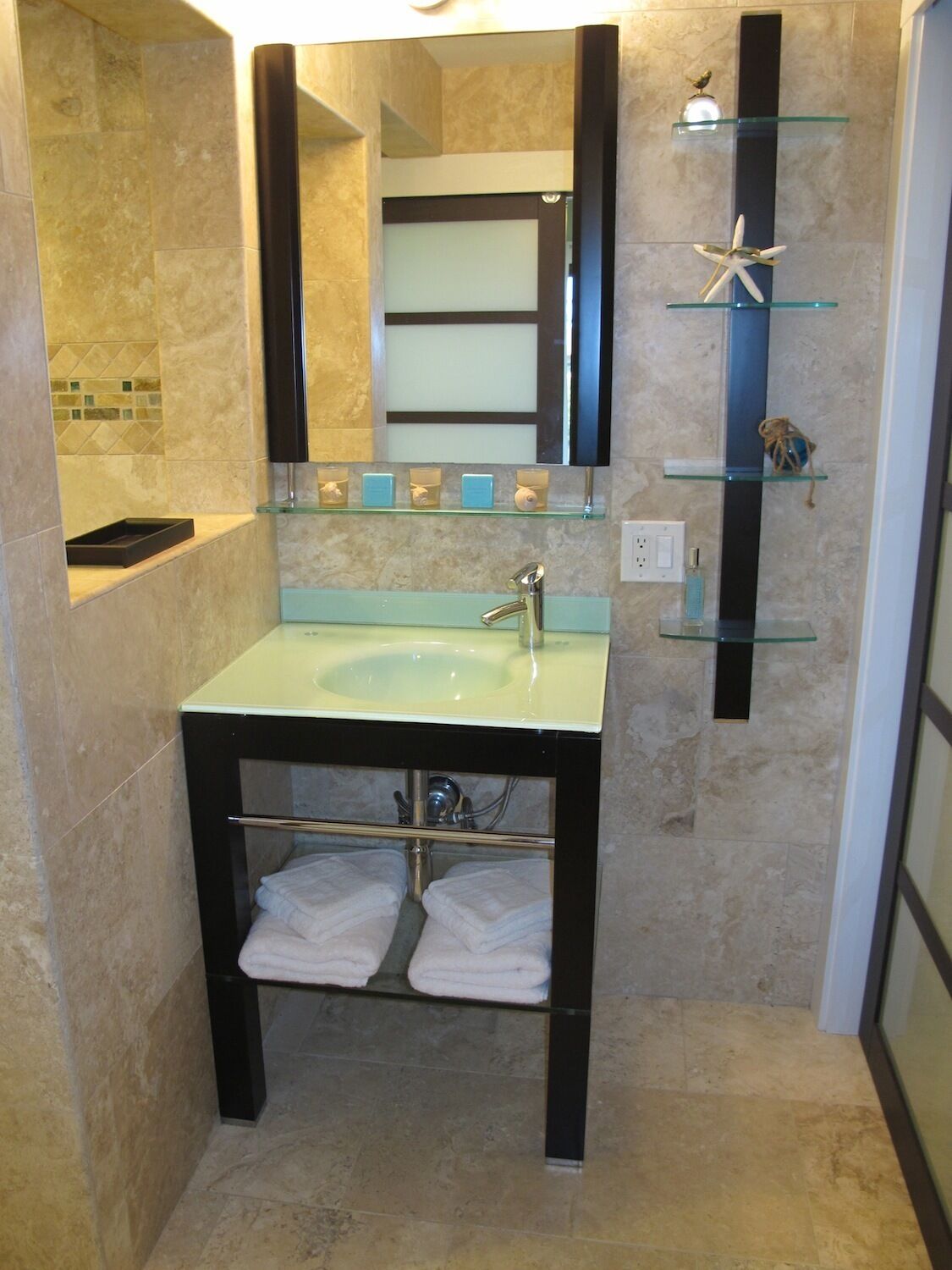 A bathroom with a sink, mirror, and shelves with toiletries.