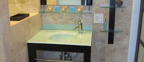 A bathroom with a sink, mirror, and shelves with toiletries.