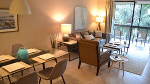 A modern living room with a glass dining table, comfortable seating, a sofa, and a view of the outdoors. - Completely Renovated And Beautifully Furnished Condo In Delray Beach... (Delray Beach)