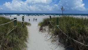 A beach pathway leading to the ocean with a grassy foreground and a clear blue sky. - Completely Renovated And Beautifully Furnished Condo In Delray Beach... (Delray Beach)