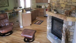 Amplia sala de estar con chimenea, comedor y cocina con armarios de madera.