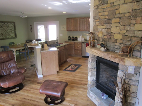 A spacious living room with a fireplace, a dining area, and a kitchen with wooden cabinets.