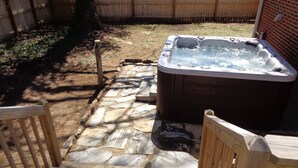 Un jacuzzi en un patio trasero con un camino de piedra que lleva a él.