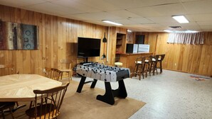 A room with a foosball table, wooden chairs, a television, and a bar area. - BEST VALUE!! SPACIOUS Home! Short Walk to Beach! Many Amenities!! Great Reviews! (Rehoboth Beach)