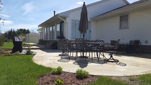 A patio with a table and chairs, a covered grill, and a covered umbrella. - BEST VALUE!! SPACIOUS Home! Short Walk to Beach! Many Amenities!! Great Reviews! (Rehoboth Beach)