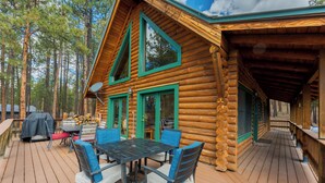 A log cabin with a deck, outdoor seating, and a covered porch.