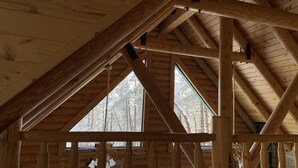 A wooden interior with a sloped ceiling and large windows.