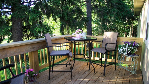 A wooden deck with two chairs and a table, surrounded by a wooden railing and trees. - Rest, Relaxation, & Quick Access to Ohiopyle Await (Ohiopyle)