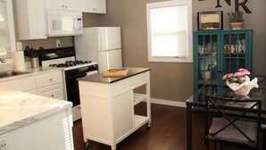 A kitchen with white cabinets, a microwave, a refrigerator, a stove, and a cart. - Rest, Relaxation, & Quick Access to Ohiopyle Await (Ohiopyle)