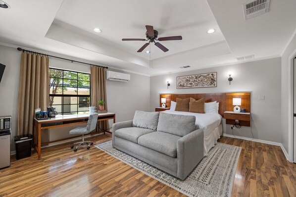 A hotel room with a bed, desk, chair, and a ceiling fan.