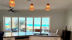Una cocina moderna con una isla grande, armarios blancos e iluminación colgante.