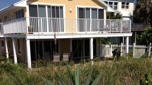 A two-story building with a balcony, surrounded by tall grass and a large agave plant in the foreground.