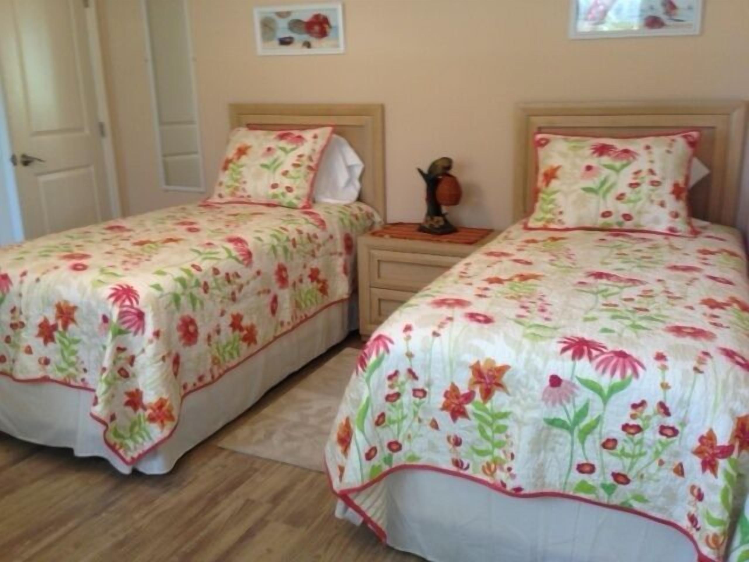 Two twin beds with floral bedding, wooden headboards, and bedside tables with lamps.