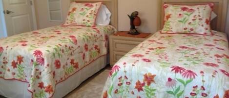 Two twin beds with floral bedding, wooden headboards, and bedside tables with lamps.