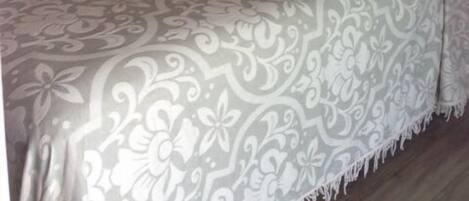 Un dormitorio con una cama grande, cabecera de madera, lámpara de noche y una planta decorativa en la pared.