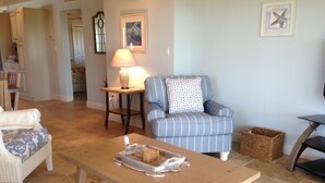 A living room with a wooden coffee table, a blue-striped armchair, and a wicker sofa.