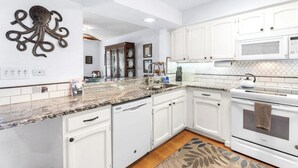 A modern kitchen with white cabinets, granite countertops, a microwave, and an octopus wall decoration. - Kitchen and Bath Remodel! - Ocean Front - Central Air - Featured on Today Show (Kailua-Kona)