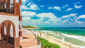 Un hotel costero con fachada de ladrillo, un balcón y vista al océano.