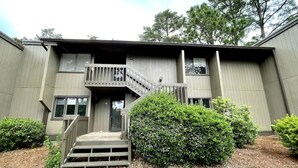 A two-story building with a wooden staircase leading to a balcony. - Upgraded 3 BR condo on Pinehurst Course 3- walking distance to main club house (Pinehurst)
