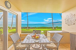 A dining area with a table set for two, overlooking a scenic ocean view. - Where Turtles and Sunsets Meet Kihei Oceanfront Condo Sweeping Ocean Views (Kihei)