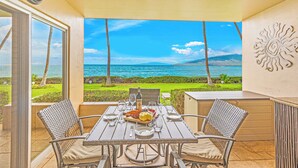 A dining area with a table set for two, overlooking a scenic ocean view. - Where Turtles and Sunsets Meet Kihei Oceanfront Condo Sweeping Ocean Views (Kihei)