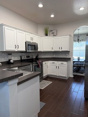 Cocina moderna con armarios blancos, microondas integrado y encimera de granito.