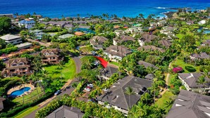 An aerial view of a coastal residential area with houses, a swimming pool, and a view of the ocean. - Regency Villas 120 - Luxury 3BR Poipu Kai Condo | Pool, Lanais & Central AC (Koloa)