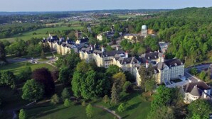 A large, historic estate with multiple buildings, expansive green lawns, and a prominent water tower. - Historic Top Floor Condo at the Grand Traverse Commons (Traverse City)