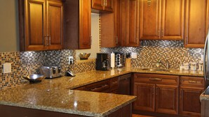 A kitchen with wooden cabinets, granite countertops, and a tiled backsplash.