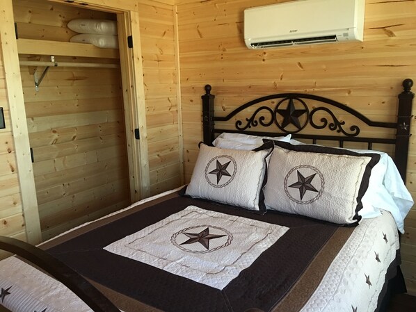 A wooden room with a bed, a wardrobe, and an air conditioning unit.