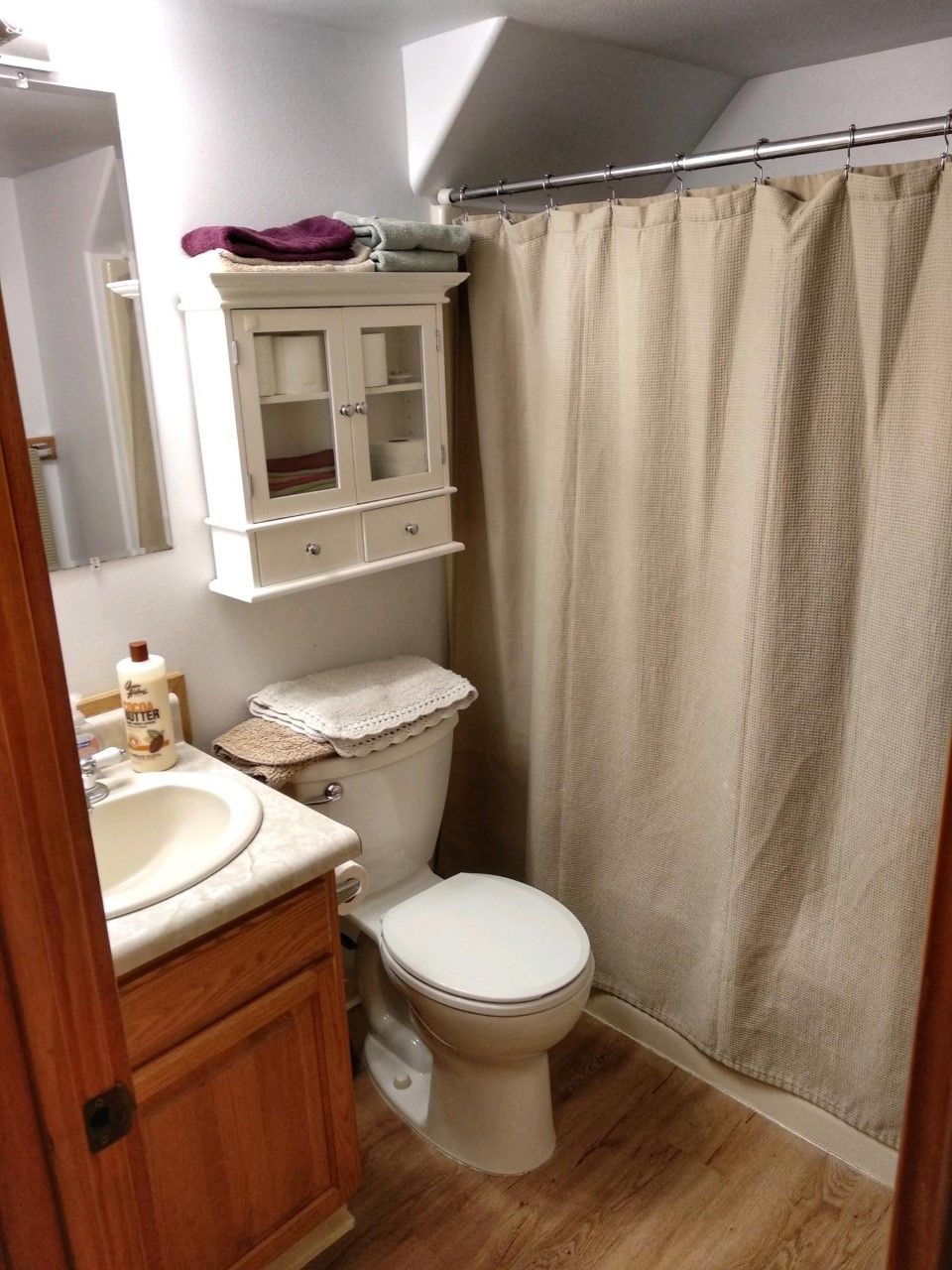 Ein Badezimmer mit Toilette, Waschbecken, Schrank und Duschvorhang.
