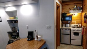 A compact kitchen with a dining table and chairs, a coffee maker, and a stove.