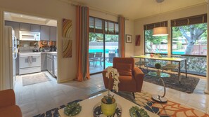 A modern living room with a sofa, a dining table, and a view of the backyard.