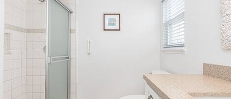 A bathroom with a shower, toilet, and sink.
