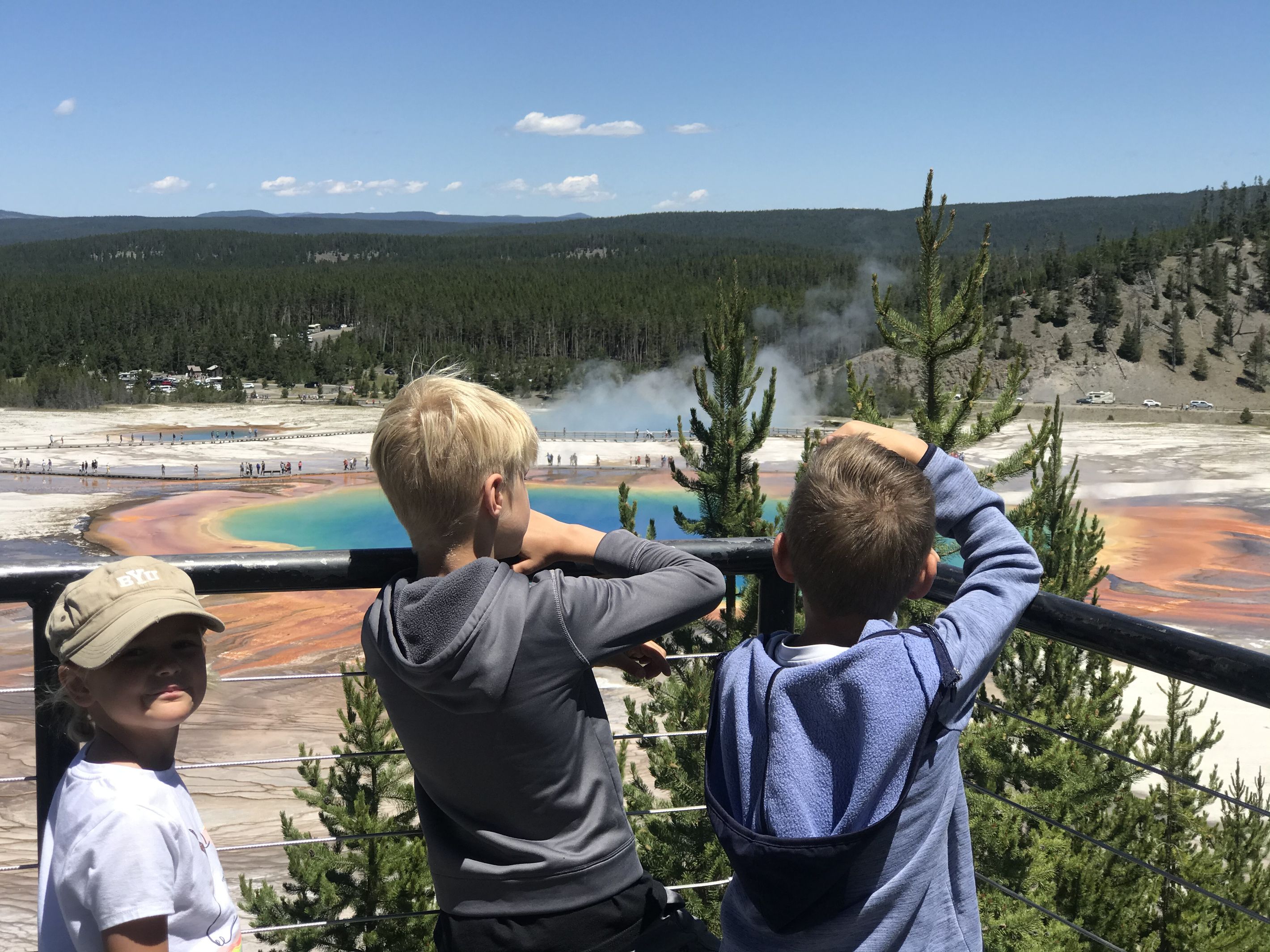 A group of people observing a geothermal area with colorful mineral deposits.