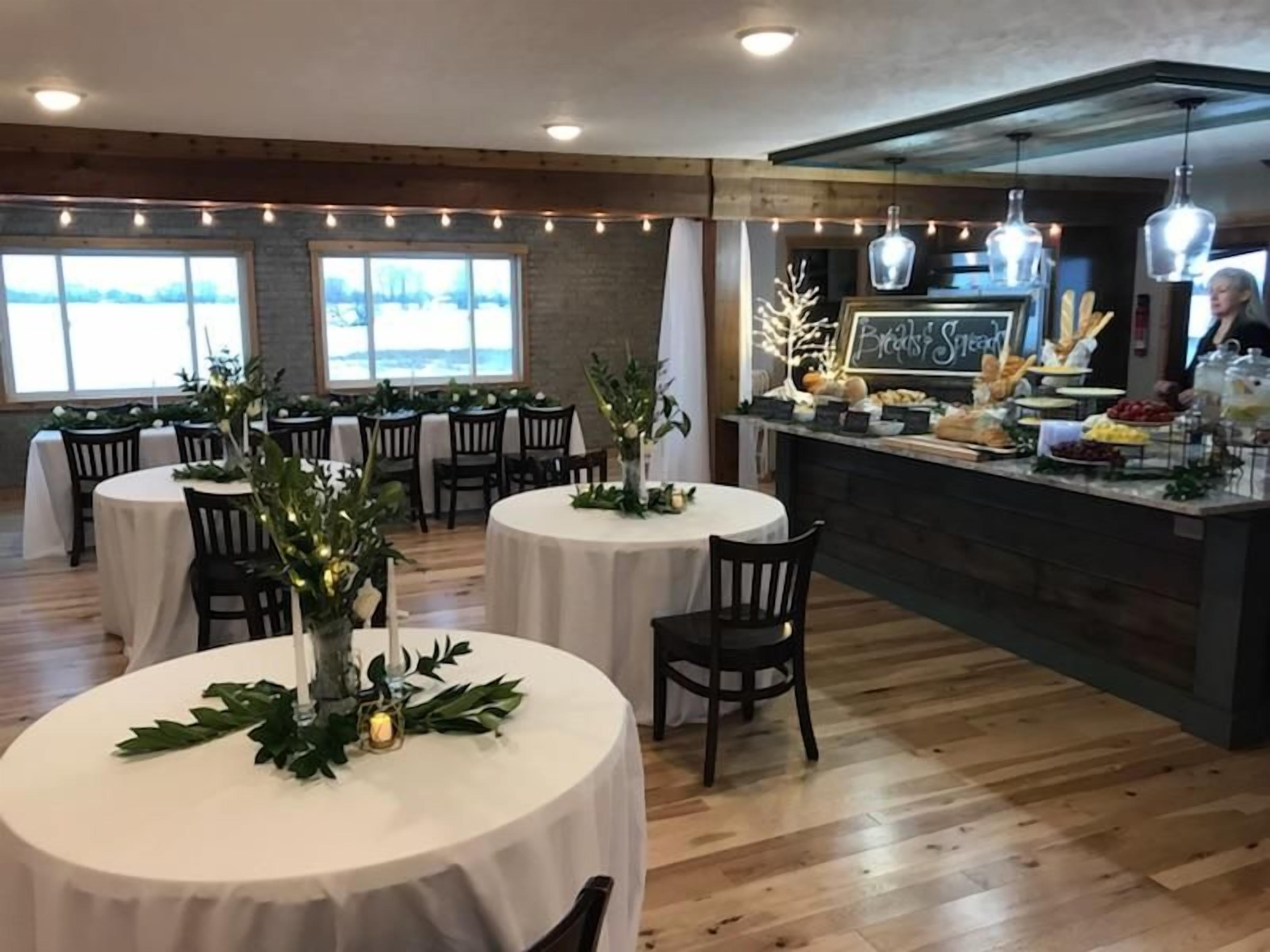 A restaurant with round tables, a bar area, and a view of the outdoors.
