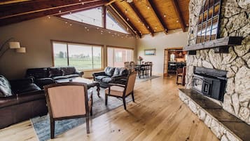 A spacious living area with a stone fireplace, leather furniture, and large windows.
