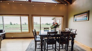 Un comedor con mesa y sillas, ventanas amplias y vistas al exterior.