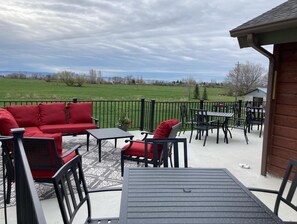 An outdoor patio with a red sofa, black chairs, a small table, and a view of a green field. - Three Peaks Lodge - Reunions, Weddings. (St. Anthony)