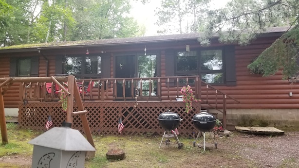 A rustic cabin with a wooden deck, a swing set, and two barbecue grills. - Horsehead Lake Retreat (Big Discounts in June Call 414-378-7273)  (Presque Isle)