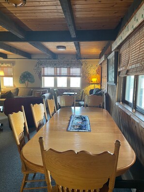 Enjoy meals in this charming dining area with a long table and six chairs, surrounded by exposed beams and beautiful floral wallpaper.