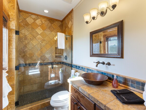 A bathroom with a glass-enclosed shower, a large bowl sink, and a vanity with a mirror. - Your Yellowstone adventure, log home for extended families, spectacular views (Livingston)