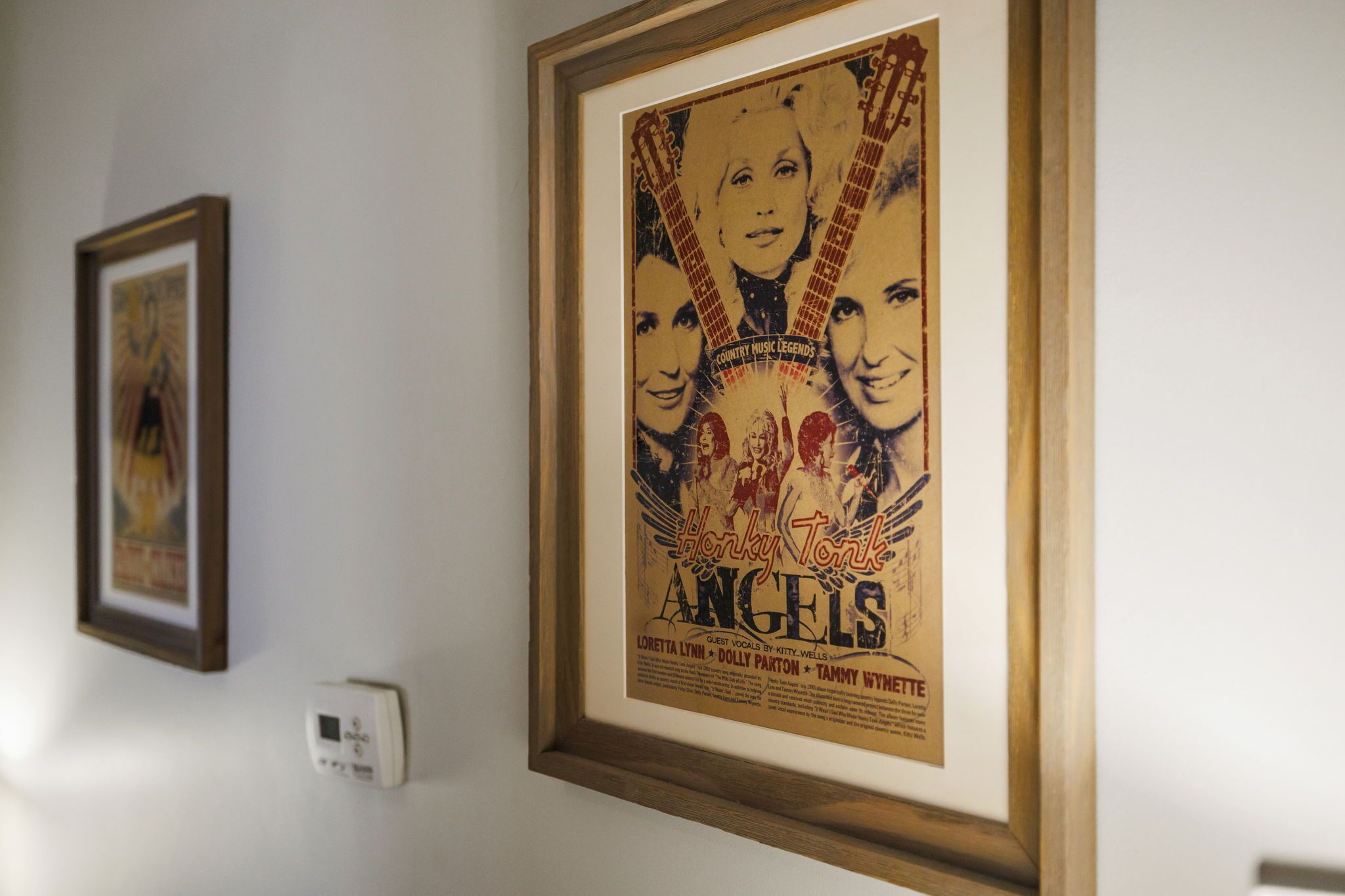 Une affiche encadrée est accrochée au mur, avec du texte et des images, et un thermostat se trouve en dessous.