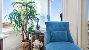 A room with a large window, a wicker plant, a blue armchair, and a decorative fish sculpture. - Touch of Paradise-Gulf Front Home Newly Renovated. Pup Friendly. Sleeps 12 (Navarre)