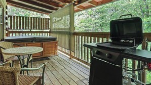A covered outdoor area with a grill, a table, and chairs.