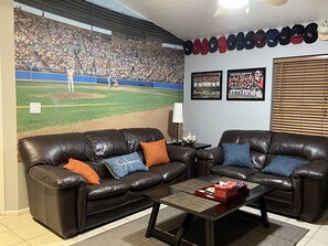 A living room with a large sports-themed mural, a leather couch, a coffee table, and a wall with framed photos. - Downtown Phoenix attached 2 king bed rooms 1 bath suite  (Phoenix)