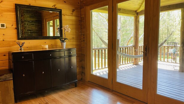 A wooden cabin interior with a black cabinet, a mirror, and a door leading to an outdoor deck.